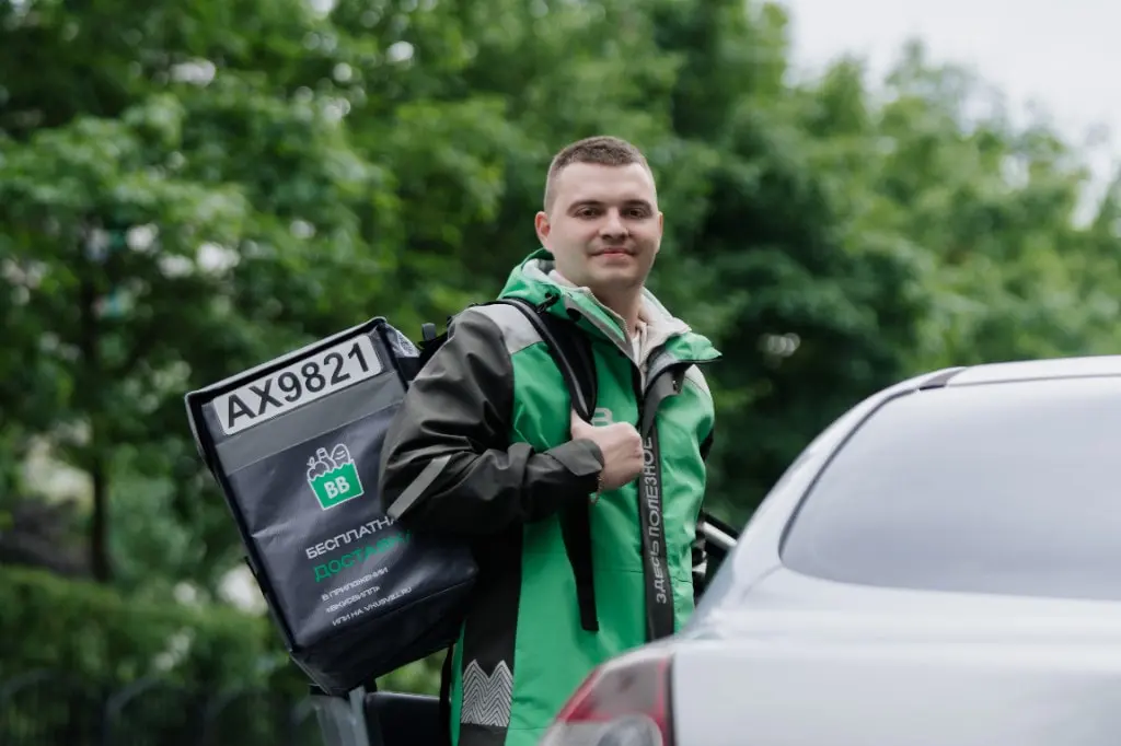 Курьер ВкусВилл с термосумкой у автомобиля